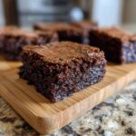 A close-up of a rich, fudgy 5-Ingredient Peanut Butter Brownies slice on a wooden board.