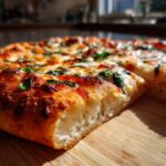 A close-up shot of a slice of easy Margherita pizza, showcasing its fluffy crust, melted mozzarella, and fresh basil.