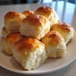 A stack of golden-brown, buttery homemade dinner rolls glistening with a glaze.