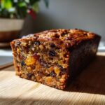 A close-up view of a rich Christmas Fruitcake with Brandy Soak, showcasing dried fruits and nuts embedded within the moist cake.