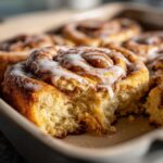 Close-up of a gooey Christmas Morning Cinnamon Roll Bake, drizzled with white icing.