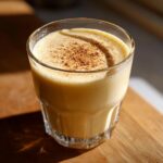 A glass of creamy Classic Eggnog topped with a sprinkle of cinnamon.