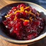 Close-up of homemade Cranberry-Orange Sauce Made from Scratch in a bowl, garnished with orange zest.