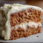 A close-up of a moist slice of Gingerbread Cake with Cream Cheese Frosting, showcasing the rich texture and creamy topping.