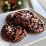 Close-up of Melt-In-Your-Mouth Peppermint Chocolate Cookies topped with chocolate chips and crushed candy canes.