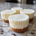 Four delicious mini cheesecake bites with a graham cracker crust, perfect for a party dessert.