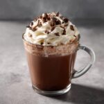 A steaming mug of rich Slow Cooker Hot Chocolate topped with whipped cream and chocolate shavings.
