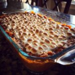 A close-up of a baked Sweet Potato Casserole with a gooey, toasted Marshmallow Topping in a glass dish.