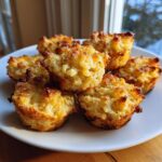 A pile of golden-brown Truffle Mac and Cheese Bites for Parties, baked in muffin tins and served on a white plate.