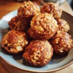 A close-up image of a pile of delicious Apple Cinnamon Oat Bites in a blue bowl, sprinkled with cinnamon.