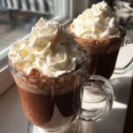 Two mugs of Baileys Hot Chocolate topped with whipped cream, perfect for a cozy treat.