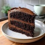A slice of delicious Baileys Irish Cream Cake on a plate, showing layers of chocolate cake and frosting.