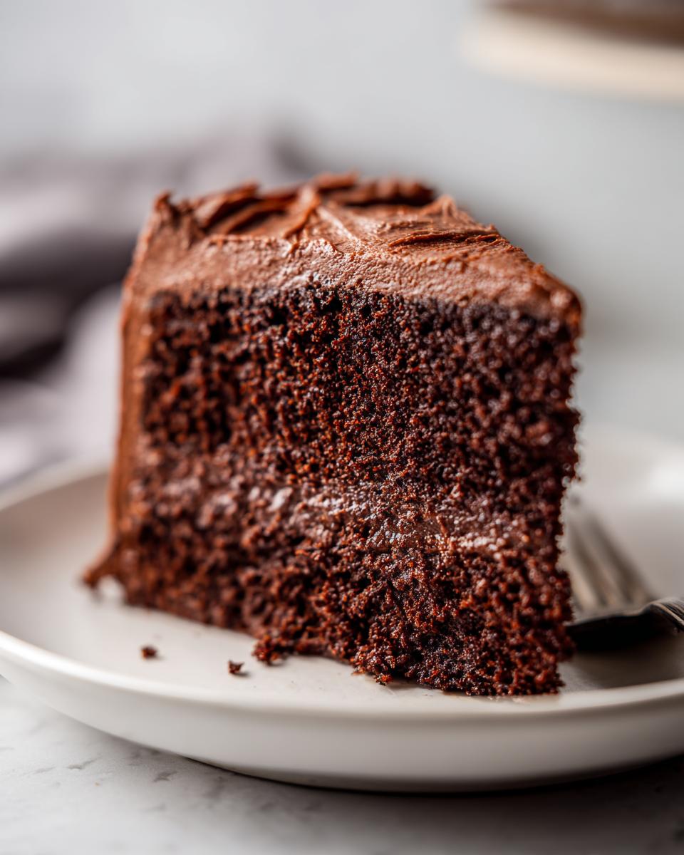 Close-up of a slice of Baileys Irish Cream Cake on a white plate with a fork.