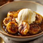 Close-up of Bananas Foster Dessert in a bowl with a scoop of vanilla ice cream.