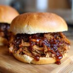 Close-up of a delicious BBQ Pulled Pork Sandwich on a wooden board, with sauce dripping.