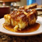 A delicious slice of Bourbon-Caramel Bread Pudding drizzled with caramel sauce on a white plate.