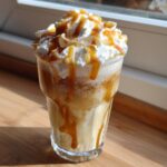A refreshing Butterbeer Float in a glass, topped with whipped cream and caramel drizzle.