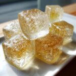 Close-up of golden Chicken Broth Ice Cubes on a white plate.