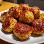 Pile of delicious, golden-brown Chicken & Sweet Potato Meatballs on a white plate.