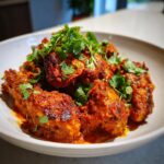 Close-up of a bowl of Chicken Tikka Masala, garnished with fresh cilantro. A flavorful Indian dish.