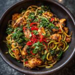 Close-up of a bowl of delicious Chicken & Zoodle Spaghetti with chicken, zucchini noodles, and herbs.