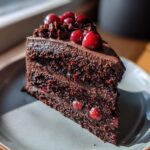 A delicious slice of Chocolate Cherry Torte, garnished with fresh cherries, on a plate.