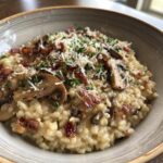 Close-up of creamy winter mushroom risotto in a bowl, topped with bacon, parmesan, and parsley.