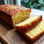 Close-up of a sliced Honey Olive Oil Cake on a wooden board, showing texture and golden crust.