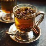 Close-up of a glass of Hot Spiced Buttered Rum, garnished with star anise and cinnamon.