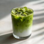 Close-up of a refreshing Iced Matcha Latte in a glass with ice cubes.