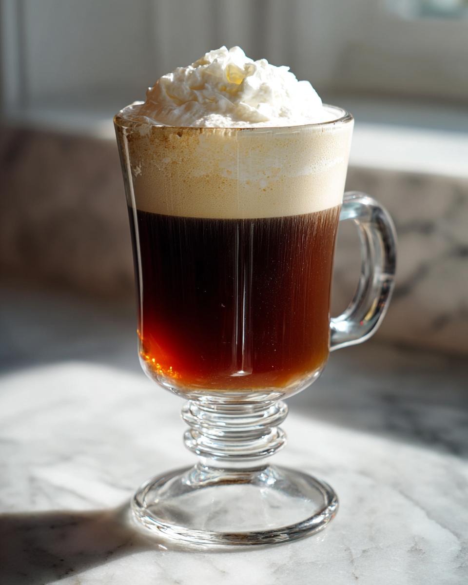 A tall glass of Irish Coffee topped with whipped cream, a classic cocktail.