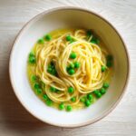 Close-up of a bowl of One-Pot Pasta e Piselli with spaghetti and green peas.