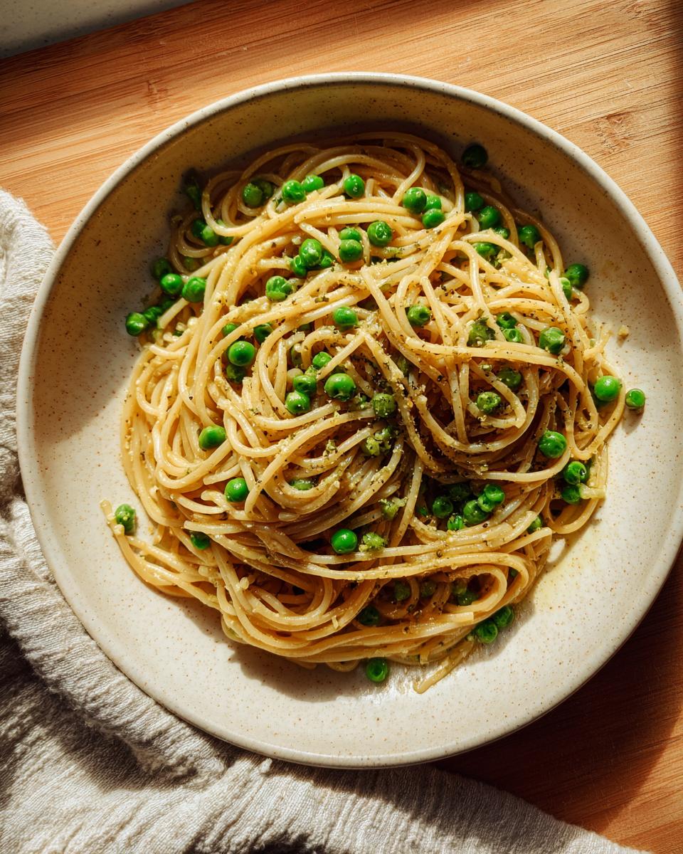 Close-up of a bowl of One-Pot Pasta e Piselli with peas and herbs.