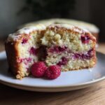Close-up of a slice of Raspberry White Chocolate Cake with fresh raspberries.