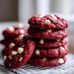 Stack of freshly baked Red Velvet Cookies with white chocolate chips on a cooling rack.