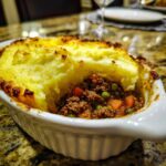 Close-up of a Shepherd's Pie in a white dish, showcasing the mashed potato topping and meat filling.