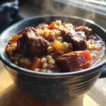 Close-up of a bowl of Slow-Cooker Beef & Barley Stew with beef chunks, barley, and vegetables.