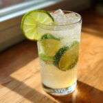 A tall glass of Spicy Ginger Lime Cooler with lime slices and ice.