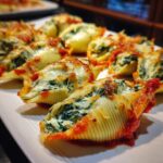 Close-up of Spinach & Ricotta Stuffed Shells on a white plate, baked with cheese and tomato sauce.