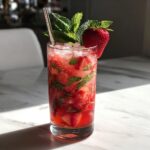 Close-up of a vibrant Strawberry Mint Mojito, garnished with mint and a strawberry.