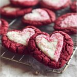 Close-up of heart-shaped Sweet Valentine's Day Swirl Cookies with white frosting and sprinkles.