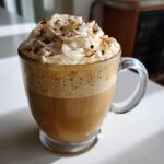 A delicious Vanilla Maple Latte topped with whipped cream and a sprinkle of cinnamon.