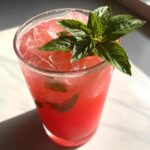 A glass of refreshing Watermelon Basil Lemonade garnished with fresh basil.