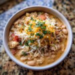 Close-up of a bowl of White Bean Chicken Chili topped with cheese and herbs.