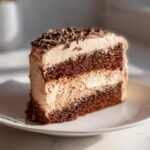 A slice of Baileys Buttercream Frosted Cake on a white plate, showing layers of cake and frosting.