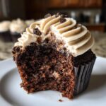Close-up of a Chocolate Guinness Cupcake with frosting and chocolate chips, bite taken out.