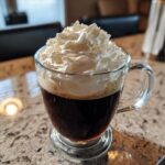 A glass of Classic Irish Coffee with a generous topping of whipped cream.