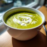 Bowl of creamy asparagus soup with a swirl of cream, perfect for a quick and easy meal. The image includes the primary keyword: Creamy Asparagus Soup.