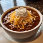 A bowl of Decadent Chocolate Chili for Two topped with cheese and sour cream.