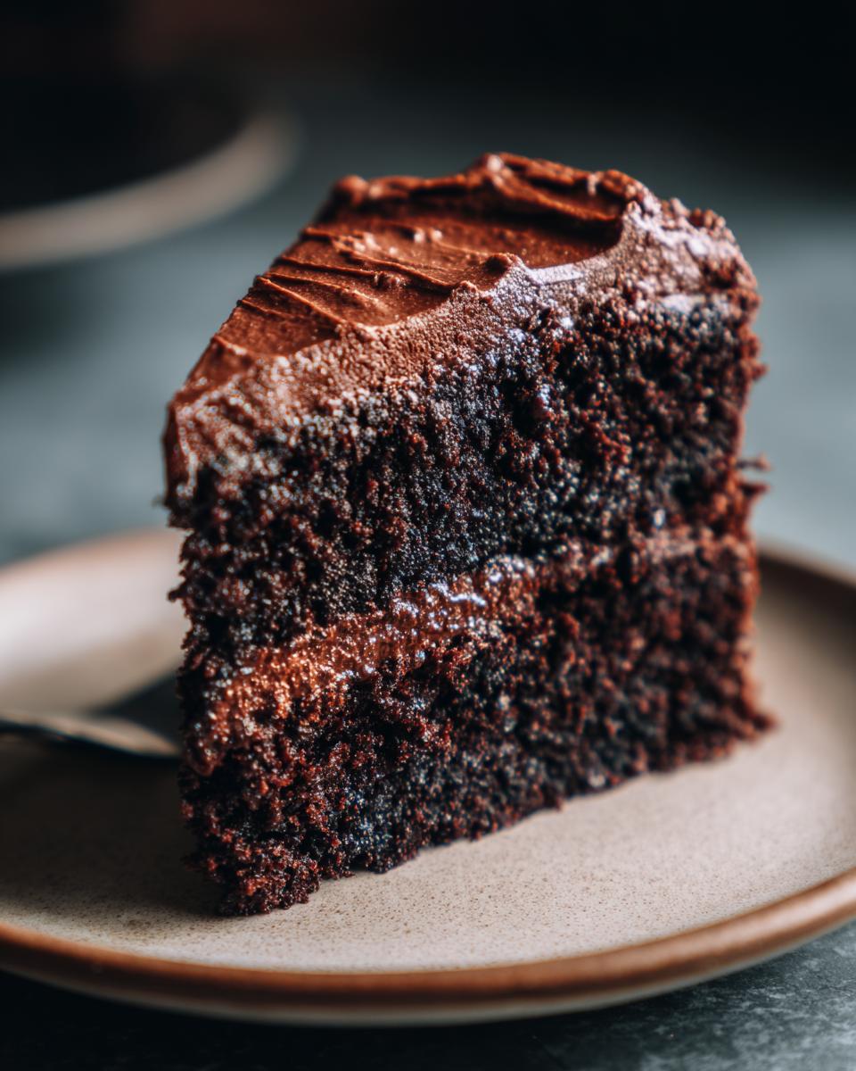 Close-up of a slice of Guinness Chocolate Layer Cake on a plate, showing the moist cake and frosting.